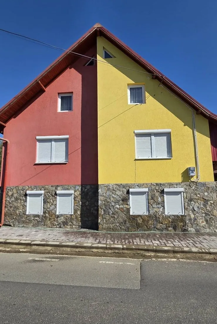 Casă cu fațadă galbenă și roșie și soclu din piatră, după spălarea fațadei