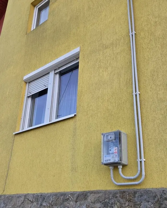 Fațadă galbenă cu tencuială decorativă pătată de ploaie, înainte de spălare